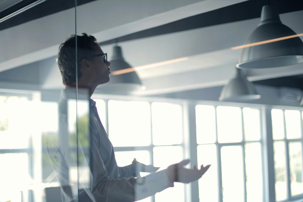 pexels photo 3760089 3760089 Business professional giving a presentation in a modern office setting through glass.